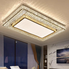 The Gio Crystal Ceiling Chandelier by Morsale, featuring a geometric design with crystal-encrusted borders and energy-efficient LED bulbs, casts a warm glow in an elegantly furnished room with floor-to-ceiling windows and walls adorned with framed artwork.