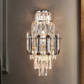The Morsale Lazzo Crystal Wall Sconce, adorned with cascading crystal prisms and mounted on a neutral-colored wall, perfectly exemplifies contemporary lighting. This LED fixture emits a warm glow that enhances the room's elegance, while its tiered arrangement of crystals beautifully reflects light.