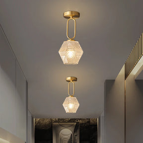 A hallway with two Morsale Palermo Ceiling Lights, featuring hexagonal glass shades and brass fixtures illuminated by LED bulbs. The light gray ceiling complements a patterned wall, extending the view along the corridor, showcasing an elegant and minimalist design in modern style.