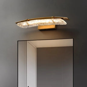 The Morsale Copper & Glass Modern LED Wall Sconce, designed with a textured glass shade and a gold base, is installed above a large mirror on a gray wall. Its energy-efficient LED lighting beautifully complements the room's contemporary decor.