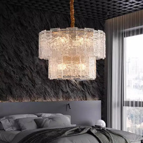 A modern bedroom with a textured dark gray accent wall features the Morsale Retford Modern Chandelier with LED bulbs hanging above a neatly made bed, casting soft light that creates a cozy, stylish ambiance.