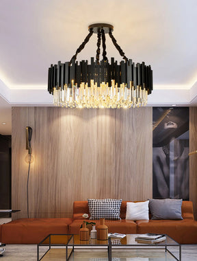 A modern living room featuring a Gio Modern Chandelier by Morsale above a brown sectional sofa. Wood-paneled walls display black and white art, while a glass coffee table holds decorative vases. Contemporary lighting enhances the warm atmosphere.