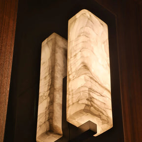The Alton Marble Wall Lamp by Morsale features two rectangular, marble-patterned light covers that create a warm glow against a dark wooden wall, embodying minimalist aesthetics and adding sophisticated charm to any kitchen space.