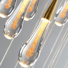 Close-up of the Pendant Light Fixture For Stairwell by Morsale.com features modern transparent teardrop-shaped pendants. Each pendant contains decorative gold specs, suspended by thin wires to create an elegant ambient lighting display.