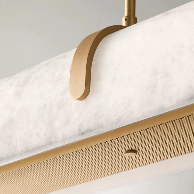 
                  
                    Close-up of the Windsor Marble & Copper Linear Pendant by Morsale, featuring a white marble tube suspended by a curved copper bracket and accented below with a perforated gold panel and a small round detail.
                  
                