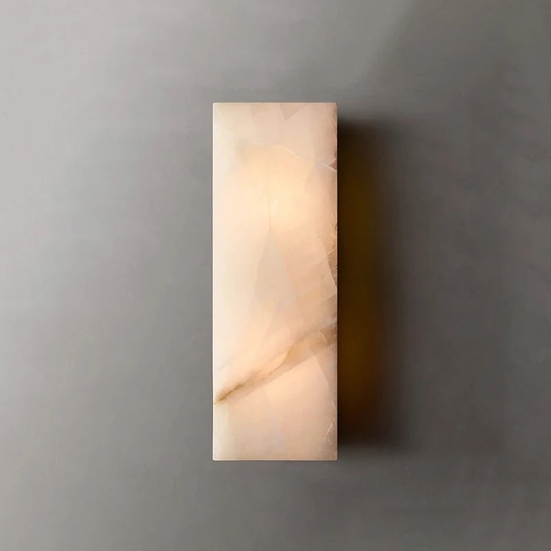 The Morsale Varenna Outdoor Marble Wall Light, a rectangular waterproof sconce, casts a warm glow on a plain gray wall.