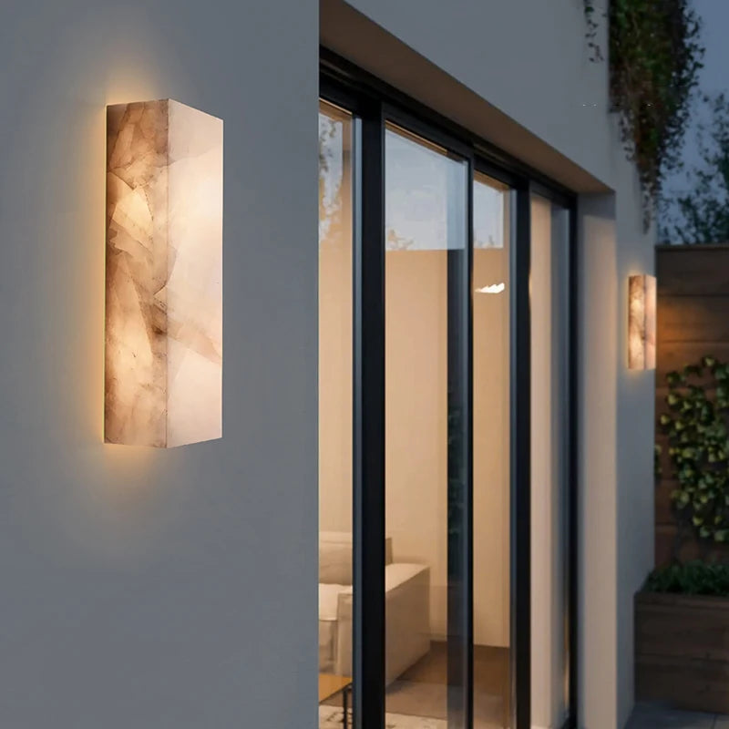 
                  
                    The Morsale Outdoor Marble LED Wall Lamp features a marble-like finish and IP65 waterproof rating, casting warm light on the exterior wall of a modern house with large glass doors and a plant-filled patio.
                  
                
