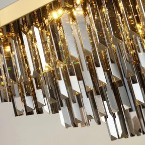 A close-up shot of the Gio Smoke Grey Crystal Ceiling Chandelier by Morsale.com featuring numerous elongated, smoke grey crystal prisms hanging from a golden frame. The crystals reflect and refract light, creating a sparkling, dazzling effect that exemplifies elegant design.