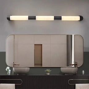 A modern bathroom showcases a large rectangular mirror above a dark gray countertop. Two white sinks with faucets are positioned on either side, while an elegant Moonshade Natural Marble Wall Lamp by Morsale, featuring black and white segments, is mounted above the mirror to enhance the sleek design.