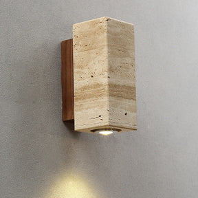 The Natural Travertine Wall Lights from Morsale.com feature a wall-mounted light fixture with a rectangular, stone-like cover and a wooden mounting base. The LED wall lamp directs light downward, casting a soft glow on the gray wall below, embodying Japan-style lighting aesthetics.