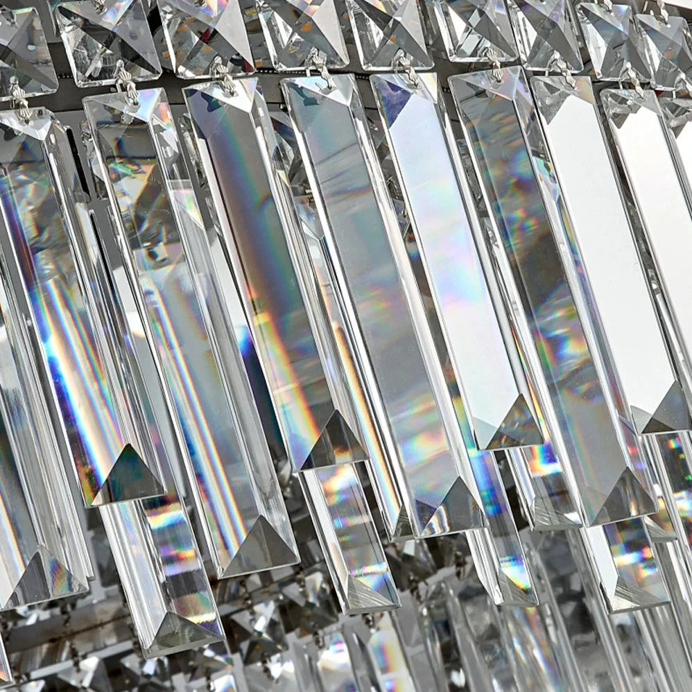 A close-up shot captures multiple handmade clear crystal prisms hanging vertically, reflecting and refracting light to produce a spectrum of rainbow colors. The arrangement is part of the Gio Flush Mount Crystal Ceiling Light from Morsale.com, with each prism displaying sharp, clean edges and a glossy finish.