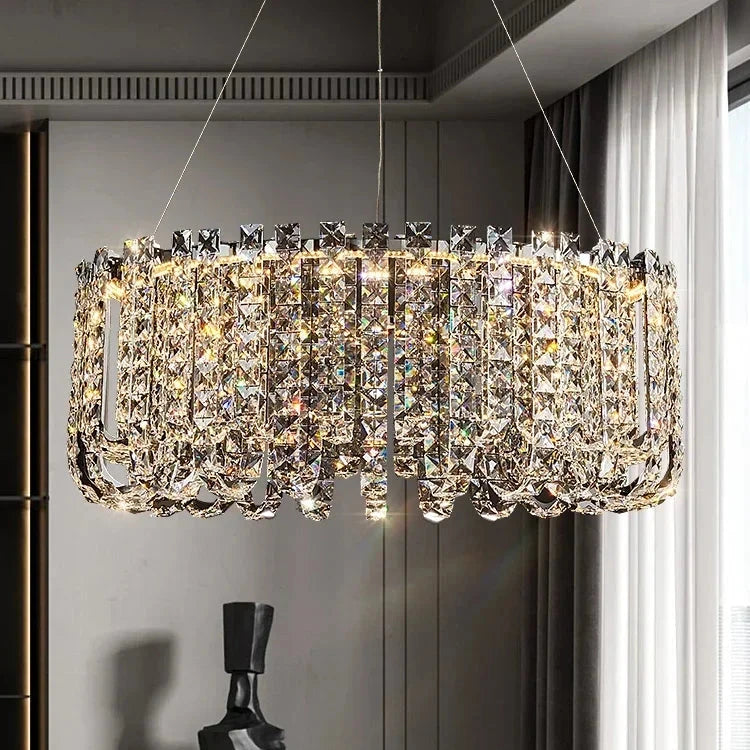 A Bacci Crystal Beads Chandelier by Morsale graces a modern room, emitting an opulent glow. This elegant fixture showcases exquisite craftsmanship with its cylindrical design and rows of shimmering prisms, amplifying the sophisticated ambiance.