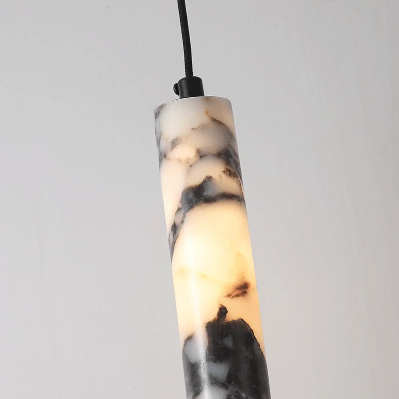 
                  
                    The Morsale Valmont Marble Cylinder Pendant Light is a sleek black marble pendant with white and gray marbling, suspended from a black cord against a light background.
                  
                