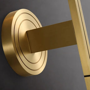 A close-up of a modern golden door handle on a circular copper base, mounted on a gray surface, showcases sleek and minimalist design elements with geometric shapes and a metallic finish that harmonizes beautifully with the Palermo Copper & Glass Contemporary Wall Sconce by Morsale.