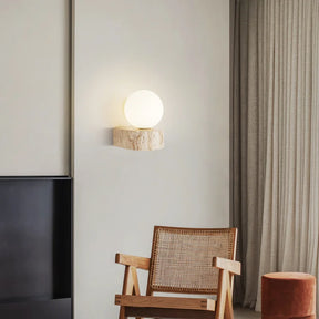 The Modern LED Travertine Wall Sconce from Morsale.com features a travertine base with natural beige and light brown patterns, topped with a large, smooth frosted globe light. Equipped with LED bulbs, the globe emits a soft, warm glow that casts gentle light on the wall.