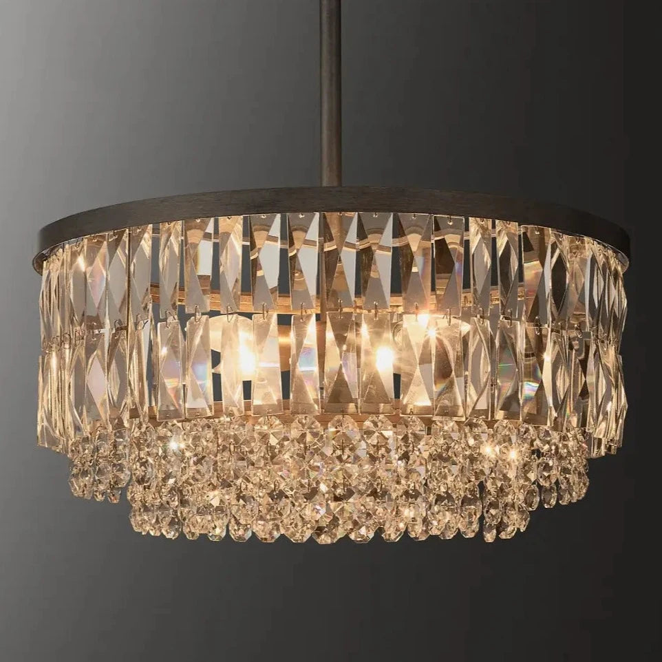 The Bacci Crystal Chandelier from Morsale.com, a luxurious fixture with a black metal frame, is suspended from the ceiling. Featuring two rows of K9 crystal prisms and hanging ornaments, it emits a warm, elegant glow against a dark background.