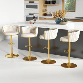 A modern kitchen features a sleek white island with four Morsale height adjustable counter stools, boasting tufted upholstery in gold. Wooden cabinets, a built-in oven, a plant arrangement, and a window backdrop complete the scene. A bottle and glasses sit invitingly on the counter.