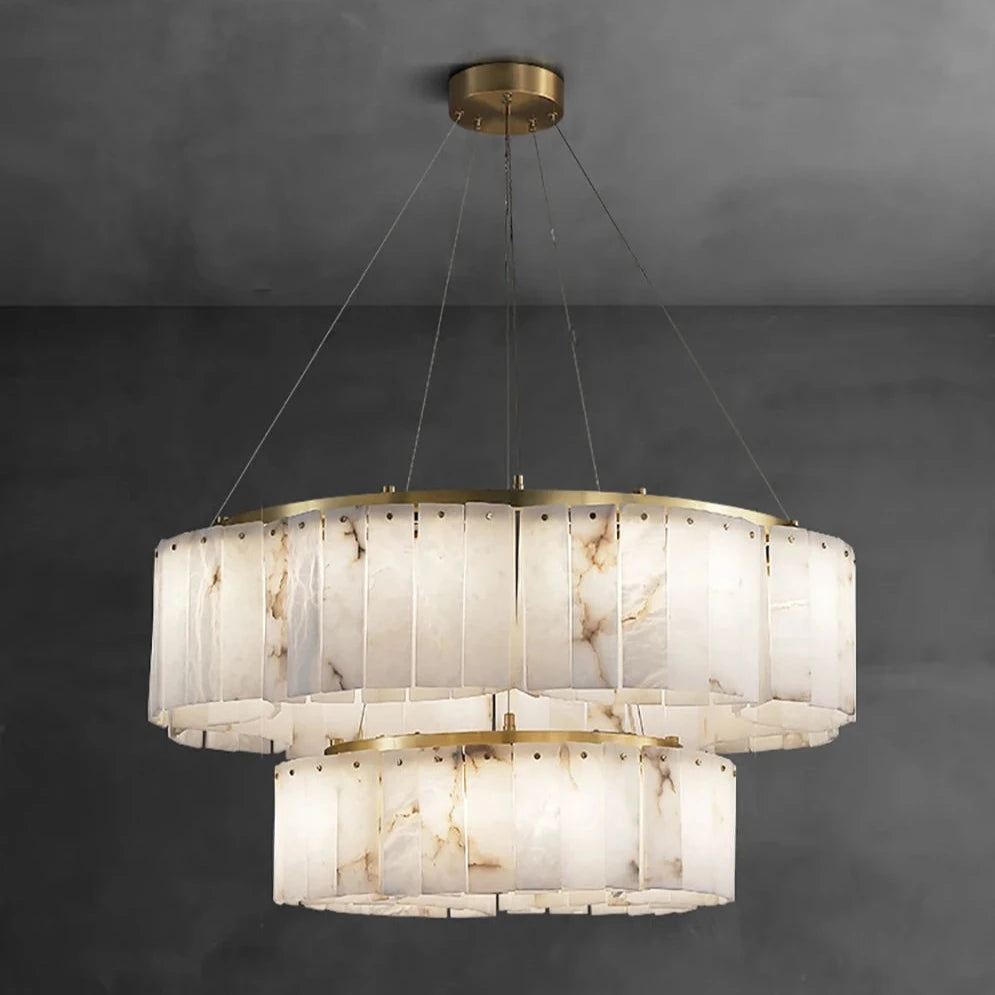 A **2-Tier Natural Marble Modern Chandelier** from Morsale.com hangs from the ceiling. Each tier features a series of vertical, rectangular panels with a marble-like texture. The light inside is turned on, casting a warm glow. Text below the fixture reads "Dia85+55cm TURN ON".