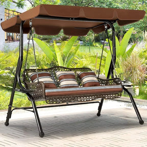 The Morsale Lewes 3-Seat Porch Swing Chair features a brown canopy and cushioned seats with striped pillows. Easy to assemble, it's perfect on a patio surrounded by lush foliage and a manicured garden—ideal outdoor furniture.