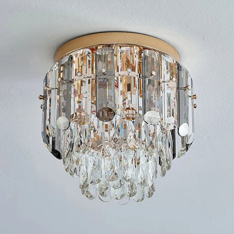 The Giano Ceiling Light Fixture by Morsale.com is a round, flush-mount ceiling light fixture with a gold base adorned with multiple tiers of clear, elongated, and teardrop-shaped handmade crystals hanging down. The crystals reflect light, creating a shimmering and elegant appearance perfect for any sophisticated space.