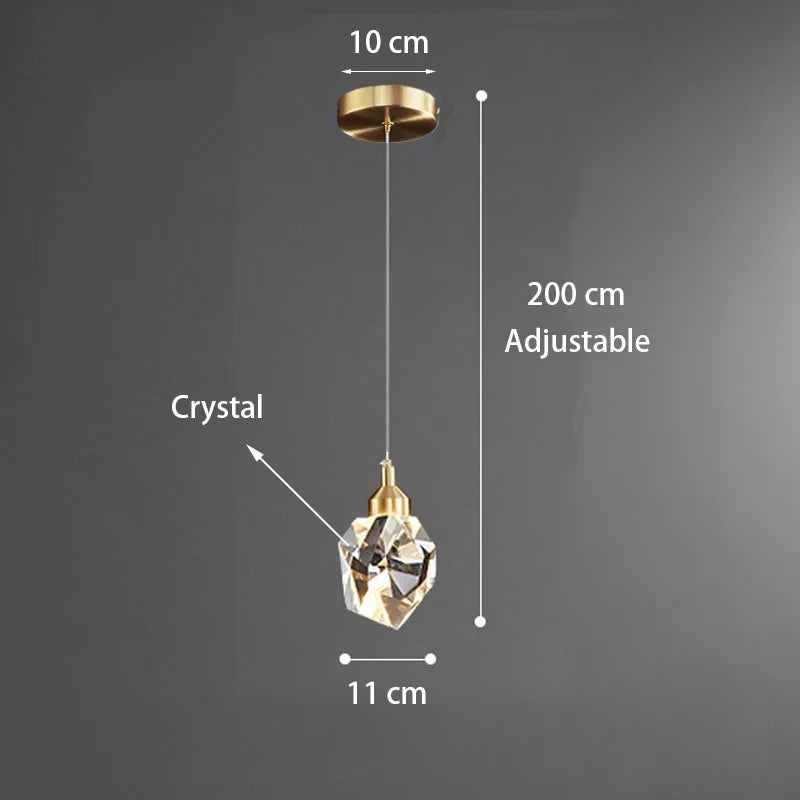 Introducing the Diamante Crystal Pendant Light by Morsale. This elegant fixture boasts a modern design with a luxurious gold finish. Standing at 200 cm tall and featuring an 11 cm crystal diameter, it seamlessly enhances any room's aesthetic. The ceiling attachment measures 10 cm in width, providing a stunning contrast against a plain gray wall.