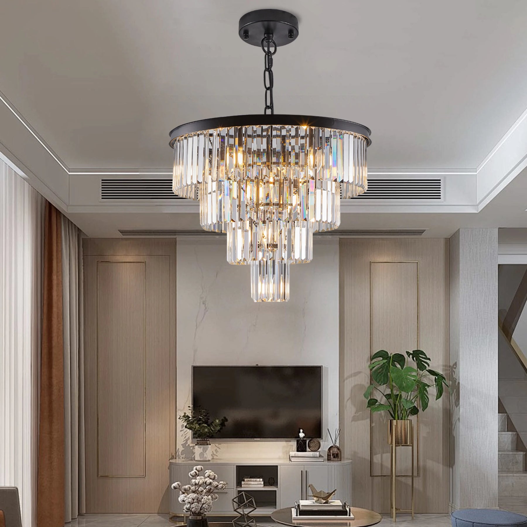 A modern living room showcases a contemporary style with the Morsale 23.6" Gio Crystal Chandelier, featuring cascading crystal rods. A TV, potted plant, and neutral-toned furniture contribute to a luxurious and cozy atmosphere.