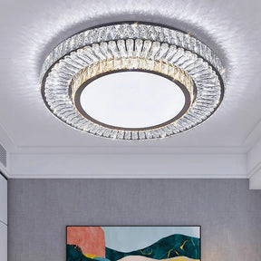 The Gio Crystal Ceiling Chandelier by Morsale, featuring glistening crystal accents and LED bulbs, illuminates the room. Below, a section of a modern abstract painting with green, pink, and black shapes stands out against the gray wall.