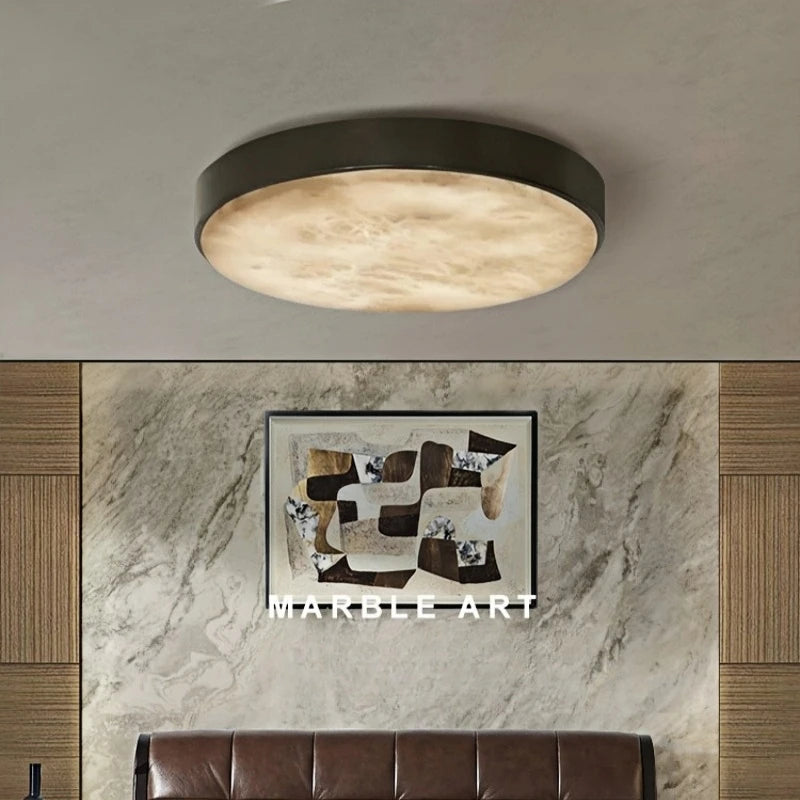 The Moonshade Marble & Copper Ceiling Light by Morsale, featuring a contemporary circular design and energy-efficient LED bulbs, brightens a space adorned with a marble art piece on the wall. A brown leather sofa rests below the artwork, enhanced by wooden panel accents.