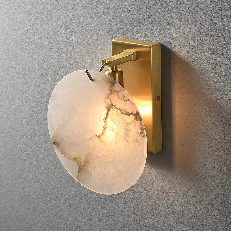 The Moonshade Marble Wall Lamp by Morsale features a modern circular marble-style shade and a gold-colored mount. Its sleek design is enhanced by a copper body that casts a warm glow on the wall.