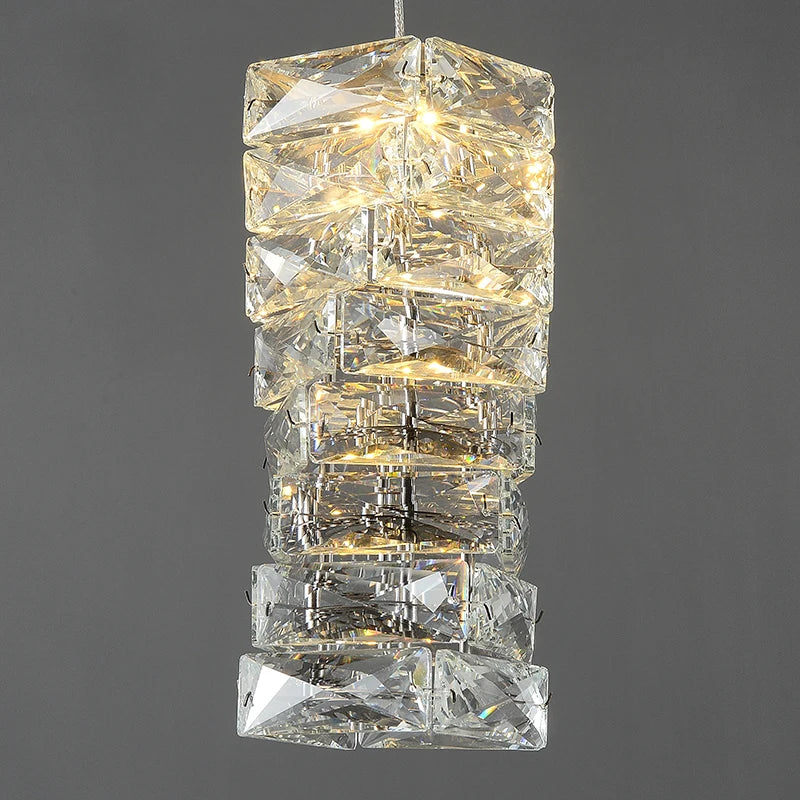A vertical stack of illuminated, square-shaped Bacci crystals forming an elegant pendant chandelier against a gray background from Morsale.com.