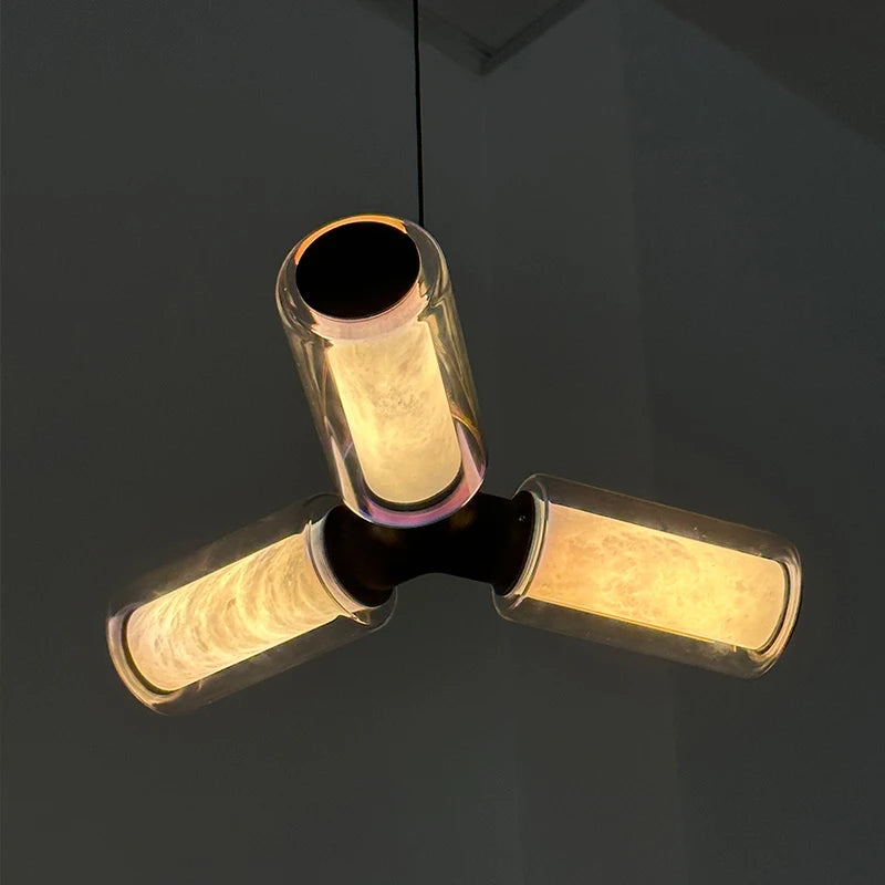 
                  
                    The Morsale Lumière Pendant Marble & Glass Suspended Light features three cylindrical LED bulbs in a triangular layout, casting a warm yellowish glow—an elegant, modern fixture perfect for stylish interiors.
                  
                