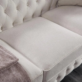 Close-up of Morsale's 3-Seat Chesterfield Sofa featuring gray tufted design and cushion seating. A folded gray blanket on the left armrest complements its fabric texture and button details, making it a stylish addition to any living room on a dark wooden floor.