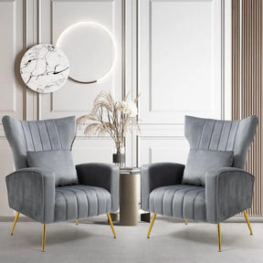 In a stylish room, the Modern Velvet Accent Chairs Set Of 2 by Morsale, featuring elegant gray upholstery and gold legs, are positioned around a small round table with a vase of dried flowers. A circular marble art piece and wooden paneling enhance the light-colored wall behind this chic display.