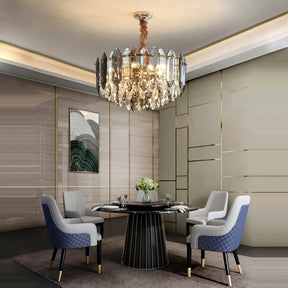 Elegant dining room featuring a round black table, surrounded by four cushioned chairs in shades of gray and blue. Overhead hangs the Lazzo Modern Chandelier by Morsale, adorned with LED bulbs for an impressive display. The light-colored walls with gold accents complement a piece of abstract art, accentuating the contemporary style.