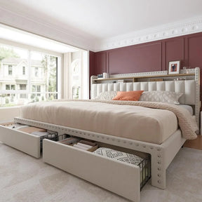 The spacious bedroom features a Morsale Verano Bed Frame with Storage and Headboard in cream-colored composite fabrics. A burgundy wall sets the backdrop, while a large window brightens the room. The headboard holds decor and a picture frame, with cream-colored carpet underfoot.