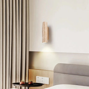 The Natural Travertine Wall Lights from Morsale.com feature a wall-mounted light fixture with a rectangular, stone-like cover and a wooden mounting base. The LED wall lamp directs light downward, casting a soft glow on the gray wall below, embodying Japan-style lighting aesthetics.