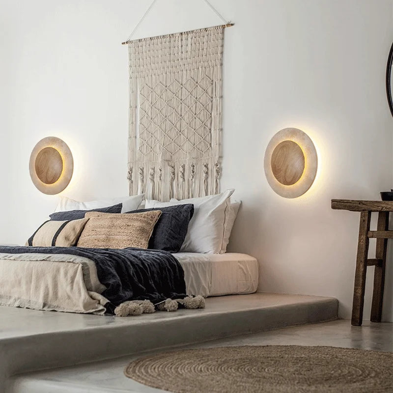 The Natural Travertine LED Decor Wall Light by Morsale.com is a modern LED wall lamp with a circular design, featuring a wooden central circle surrounded by a stone-like ring, both illuminated with a soft, warm glow. Blending Art Deco style and daily lighting needs, this piece creates a serene and ambient atmosphere.