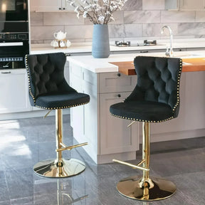 A pair of Morsale's Counter Height Swivel Bar Stools with black velvet tufting and gold bases enhance a modern kitchen with a white island countertop adorned by flowers, complemented by light cabinetry and stainless steel appliances for a cohesive contemporary look.