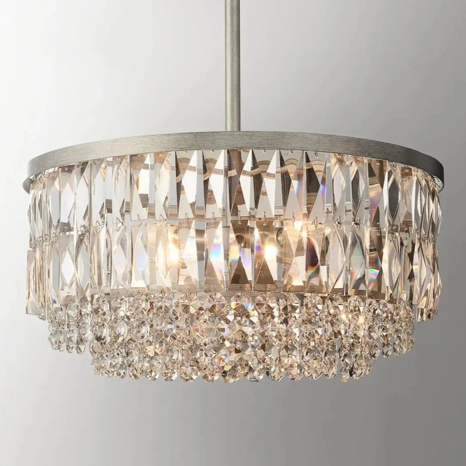 A close-up of the luxurious Bacci Crystal Chandelier from Morsale.com showcases its elegant round metallic frame. This exquisite chandelier features two tiers of dazzling K9 crystals; the upper tier is composed of vertically arranged elongated crystals, while the lower tier is adorned with intricate smaller crystal beads.