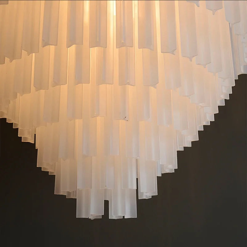 Close-up of the Morsale Frost White Crystal Chandelier, featuring cascading rows of translucent, vertical glass panels. Softly illuminated by LED bulbs, this chandelier creates a warm and elegant glow against a dark background.