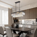 Modern dining room with a dark wood table, six cushioned chairs, and the Morsale Gio Crystal Dining Chandelier with faceted clear crystals and an electroplated gold finish. Wood cabinets, a marble backsplash, and natural light through sheer curtains complete the look.