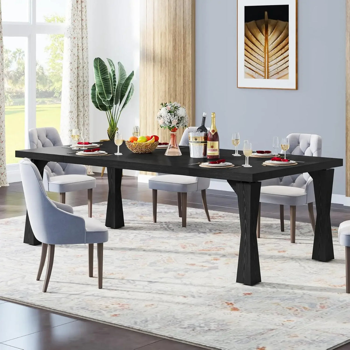 In a dining room, the Morsale Boston 70" Modern Dining Table with a two-tone finish is set with wine glasses, plates, and a fruit basket. Six white upholstered chairs surround it. A plant sits nearby, while a large window and patterned rug enhance the decor.