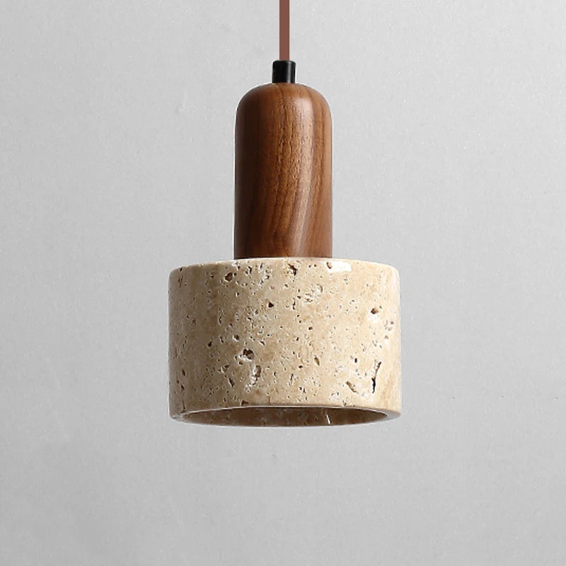 A minimalist kitchen features two Morsale.com Natural Travertine Pendant Lamps with wooden tops and stone-like concrete shades, illuminated by LED bulbs, hanging above a light wood table with a shallow wooden bowl. The background includes a marble backsplash and a counter with minimal décor.