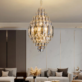 A luxurious Lazzo Crystal Modern Chandelier by Morsale with LED bulbs hangs from the ceiling, casting a warm glow over the modern style living room. The space features a light sofa, contemporary panel walls, and a small table adorned with a vase of dried flowers.