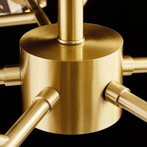 Close-up of a brass cylindrical hub with several smooth rods radiating out, all featuring a polished golden finish, designed as part of an Olga Multi Pendant Modern Chandelier, set against a dark background.