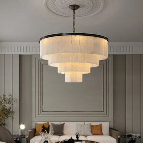 Morsale's Moonshade Marble Chandelier adds a modern touch to the living room, featuring soft yellow lighting and ambiance control via a dimmable touch switch. The space includes a neutral palette, white decorative ceiling, cushion-adorned sofa, and potted plant.