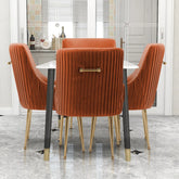 A dining room showcases a modern table with Morsale's Modern Glam Boucle Pleated Velvet Dining Chair Set of 4, featuring luxurious orange velvet upholstery and gold legs. Behind it sits a glass door with curtains, next to a small shelf displaying wine bottles and glasses on chic gray marble flooring.