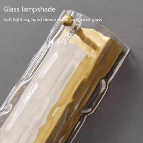 A detailed view of a Postmodern Luxury Glass & Copper Wall Light by Morsale, featuring a contemporary water-patterned glass lampshade. This hand-blown piece is elegantly tinted with white and gold colors, providing a soothing glow. Text reads "Morsale LED wall lamp: Subtle illumination with hand-crafted water patterned glass.