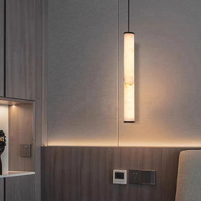 A modern interior wall features a sleek, vertical light fixture emitting a warm glow. The wall is a mix of light gray and wood paneling, complemented by a control panel and electrical outlet. Nearby, the Natural Marble & Brass Pendant Light Fixture from Morsale.com with its polished copper finish enhances the minimalist design's contemporary ambiance.