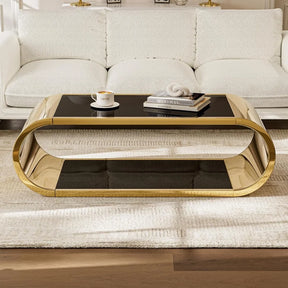 A luxurious living room showcases a white textured sofa and the elegant Morsale Stainless Steel & Glass Coffee Table, featuring a glossy black top with gold frame. A coffee cup and book rest on a light beige rug over wooden flooring, enhancing the exquisite scene.